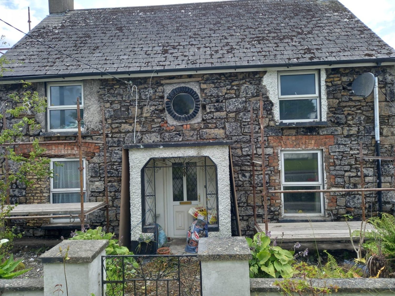 Cement dash render being stripped off a house in Mullingar, exposing the stone and brick window reveals