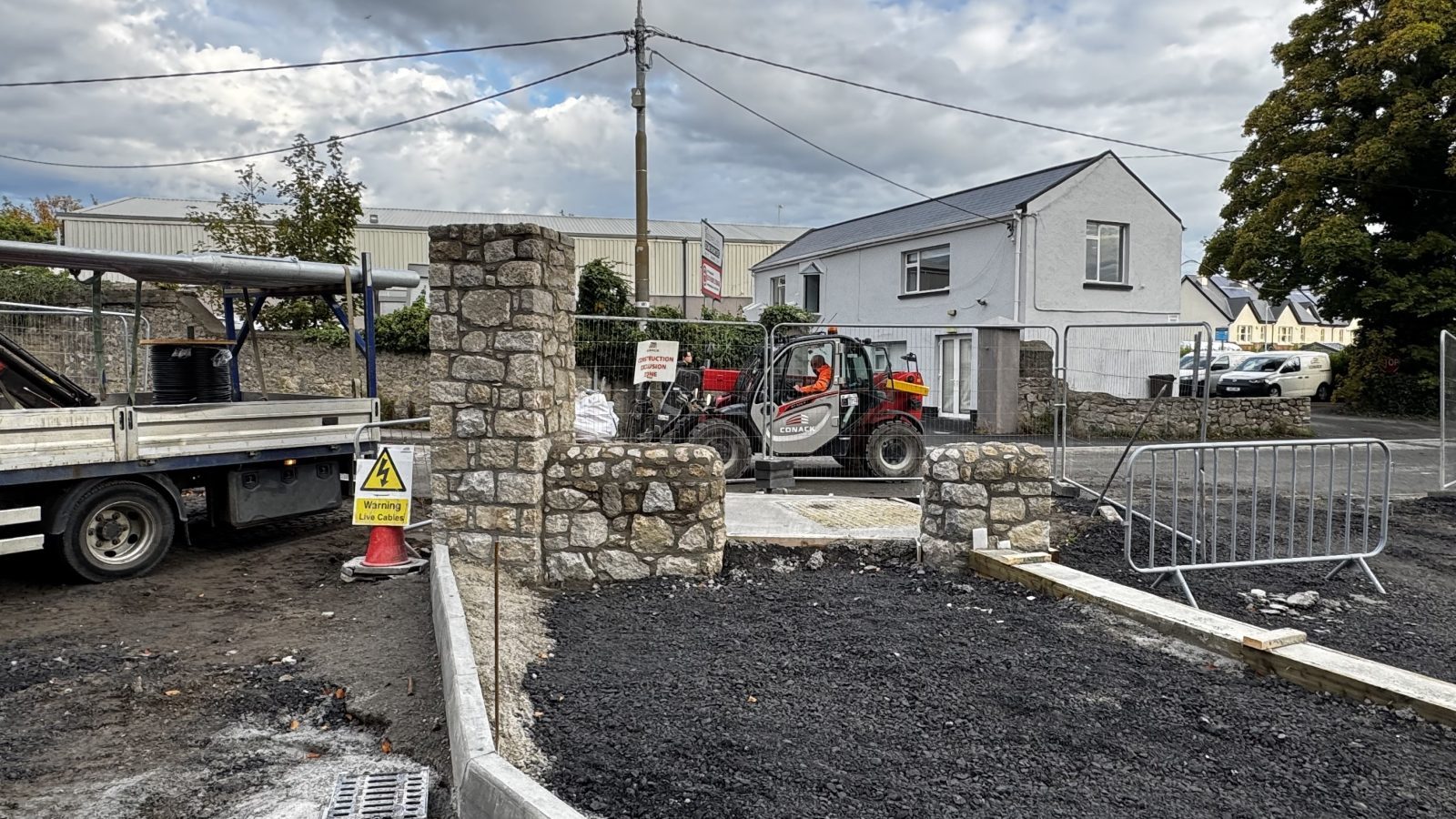 Granite rubble boundary wall and stone pillar being built by hand, Dublin
