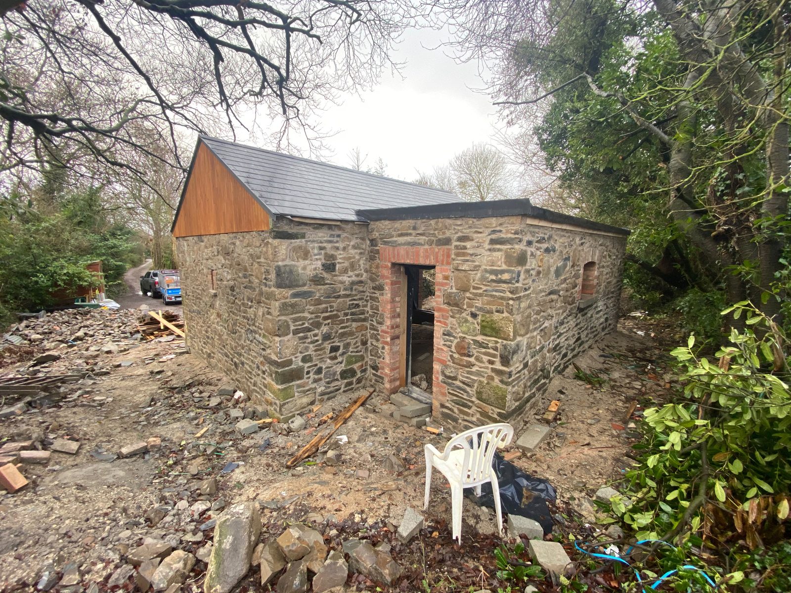 Restored rubble stone outbuilding with red brick door and window surrounds