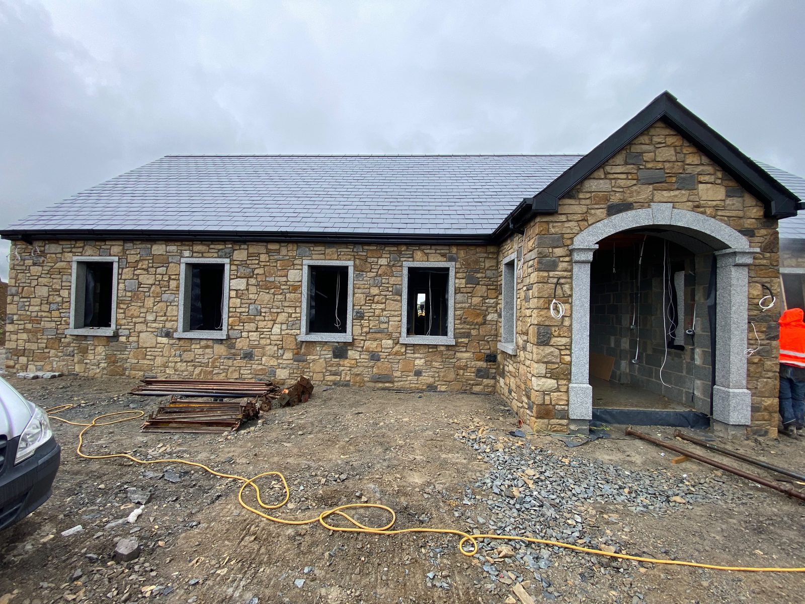 Stone-clad bungalow with cut granite window surrounds and an arched porch