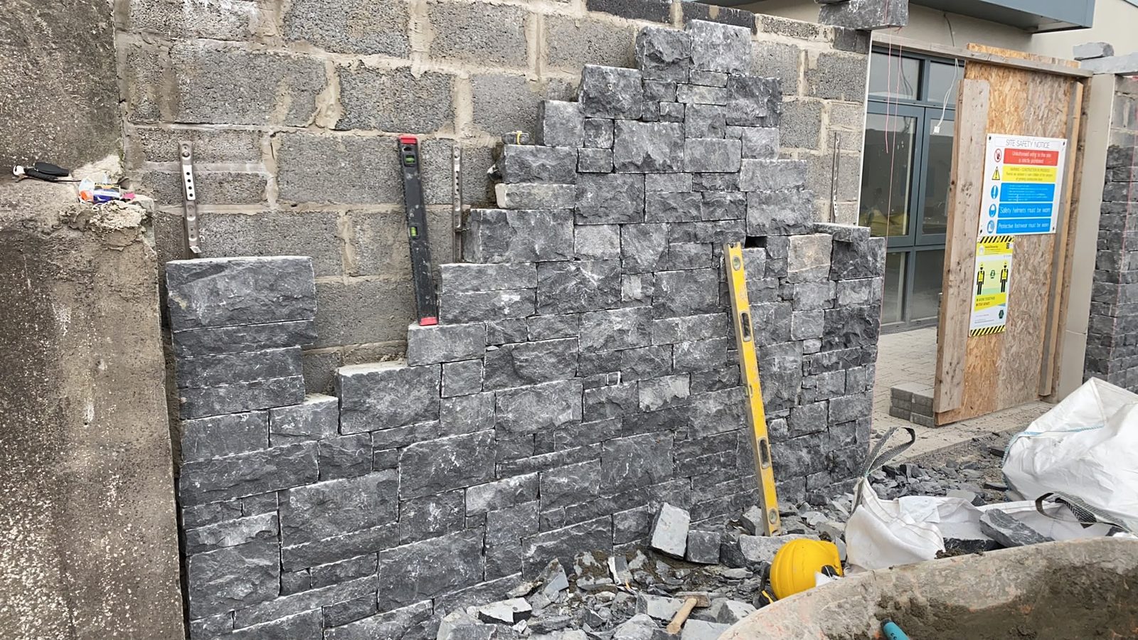 Dark limestone facing being built onto blockwork with stainless wall ties and spirit levels