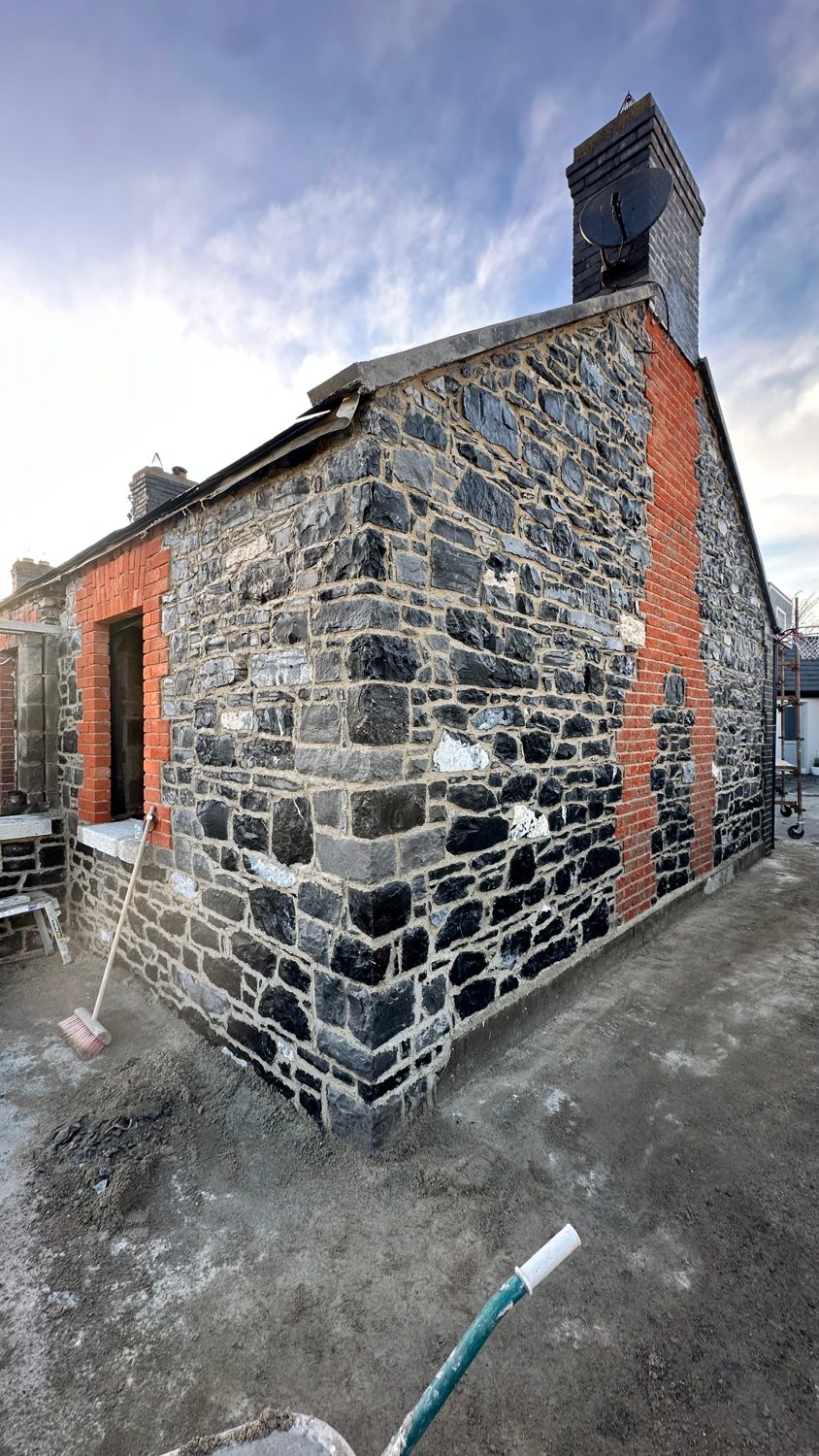 Reclaimed-brick chimney rebuilt on restored stone cottage gable, Swords