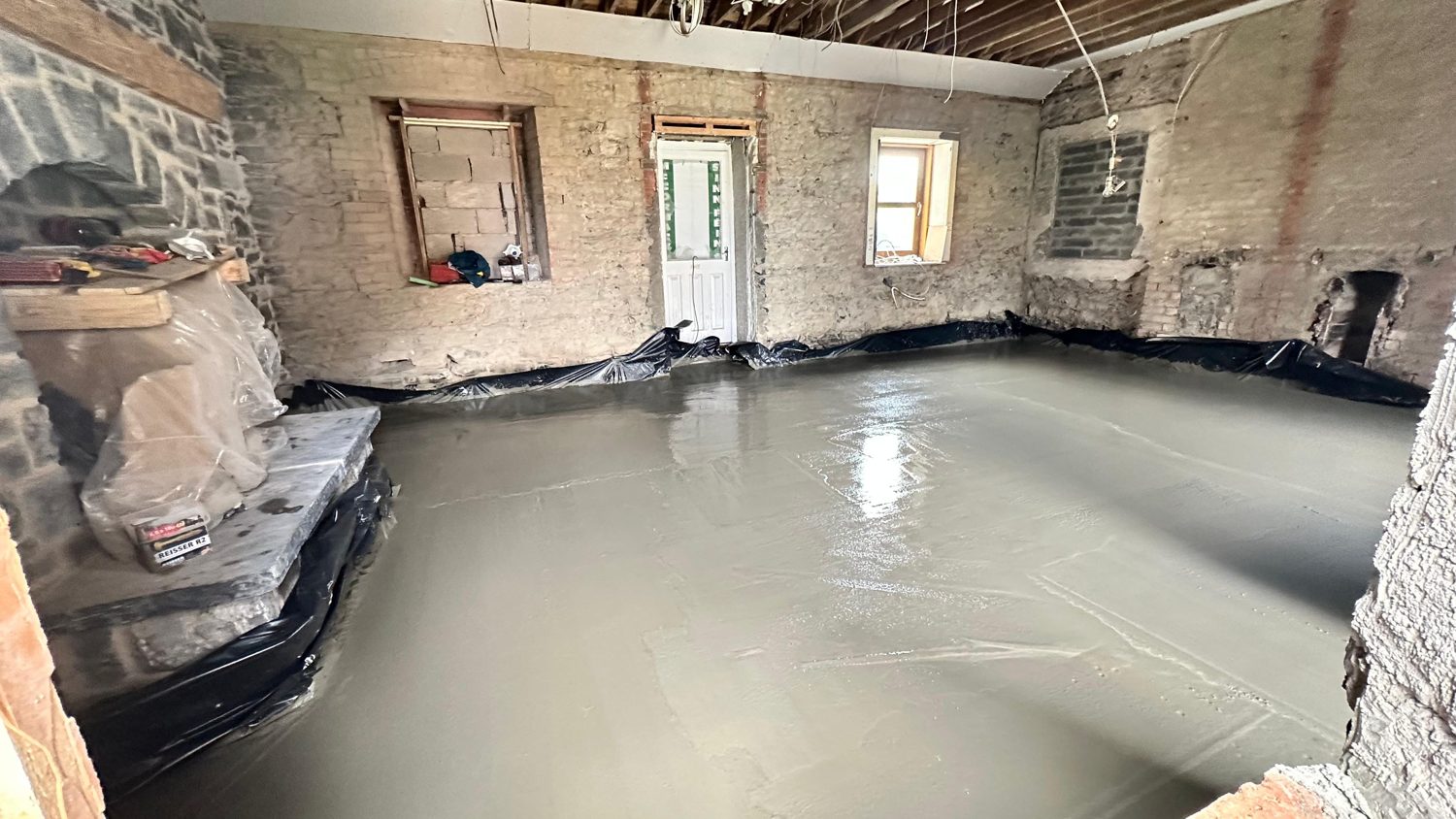 New damp-proofed concrete floor slab poured in restored stone cottage, Swords