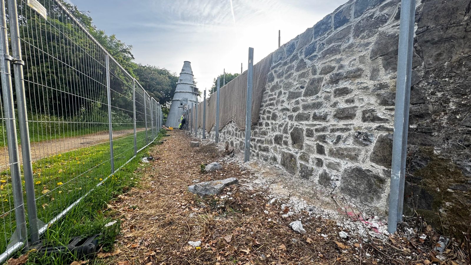 Historic boundary wall being repointed in lime mortar, with the corkscrew tower of The Wonderful Barn beyond