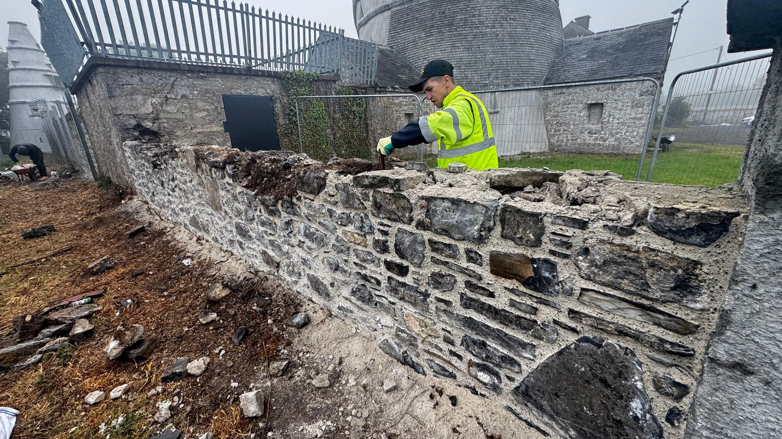 Stonemason rebuilding a failed section of historic wall by hand at The Wonderful Barn, Leixlip